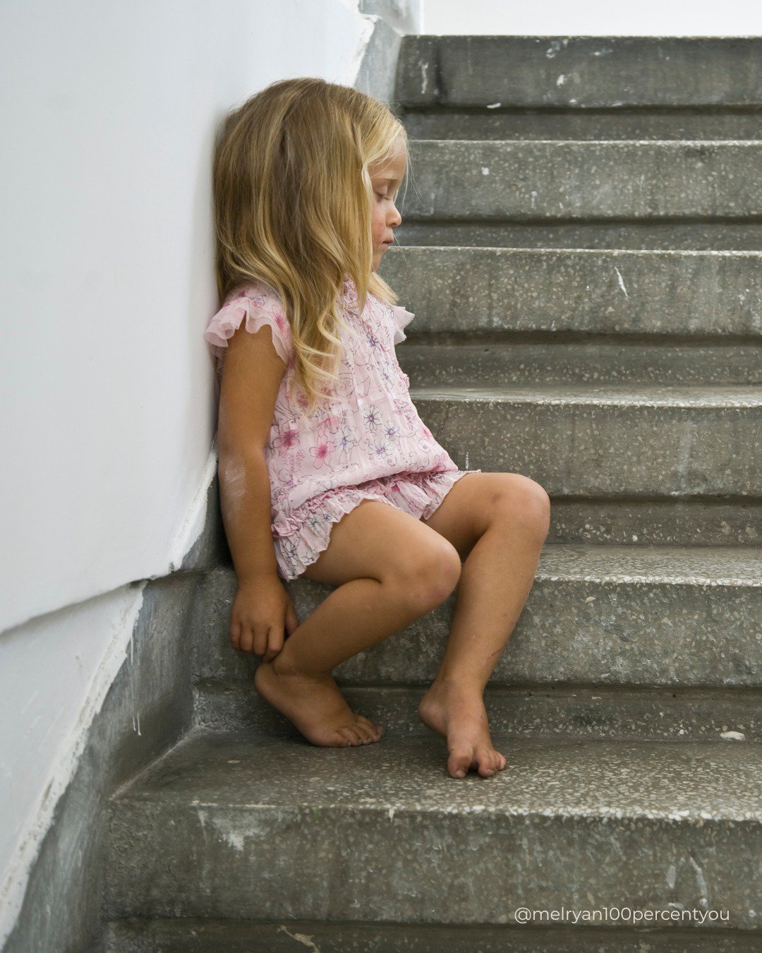 little girl sits on steps by herself